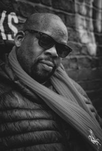 Black and white picture of Iroro looking towards camera wearing sunglasses