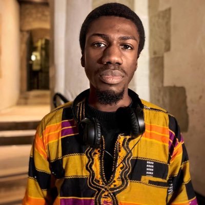 A man with headphones around his neck and yellow patterned shirt