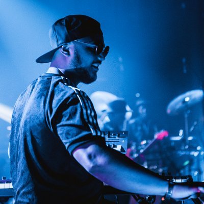 A man in a backwards baseball cap and sunglasses performing on stage