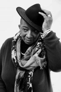 A woman with a scarf, tilts her hat