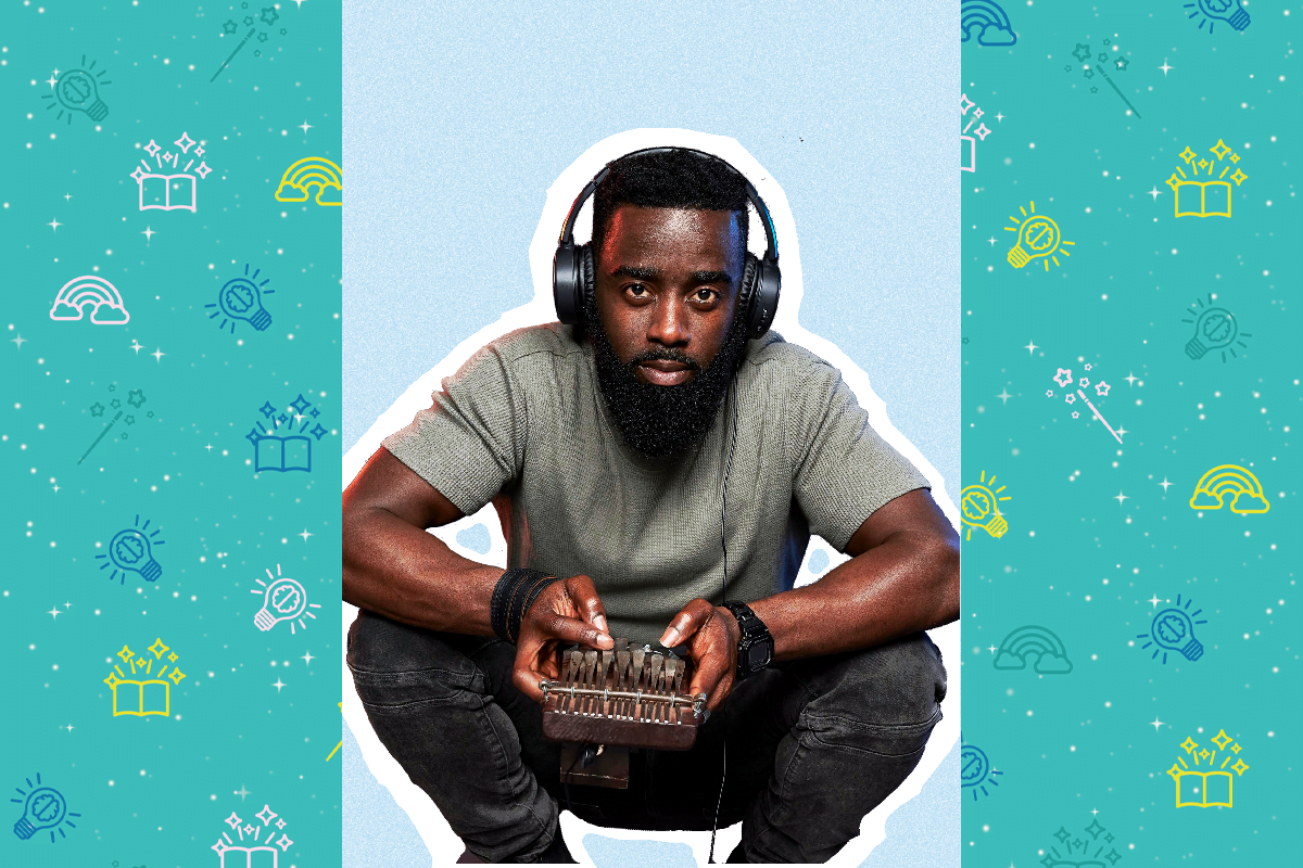 Artist Alim Kamara, he is squatted on his haunches, he wears a grey t-shirt and blue jeans. He wears black headphones over his ears and has short black hair. He holds a small instrument in his hands called an Mbira. You can pluck the metal prongs to make a sound.