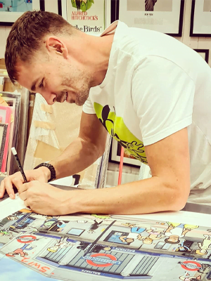 A man in white t-shirt learns over a desk to draw