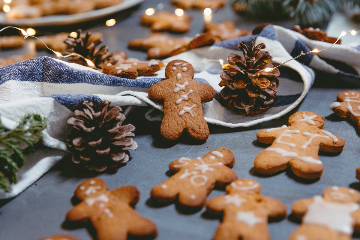 Close up of table with gingerbread people biscuits, pine cones, fairy lights