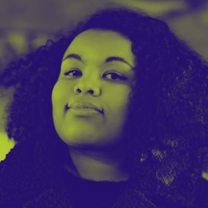 A woman with large curly hair smiles at the camera