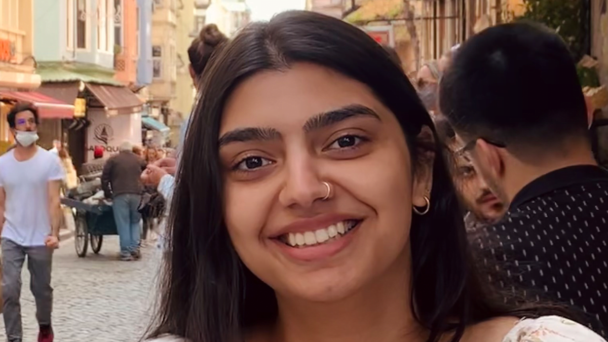 A woman with long hair hair and a small silver nose ring piercing, smiling