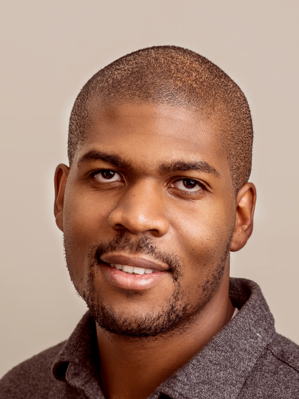 Obinna has short shaved head and landscaped beard, wearing a dark grey woollen shirt.