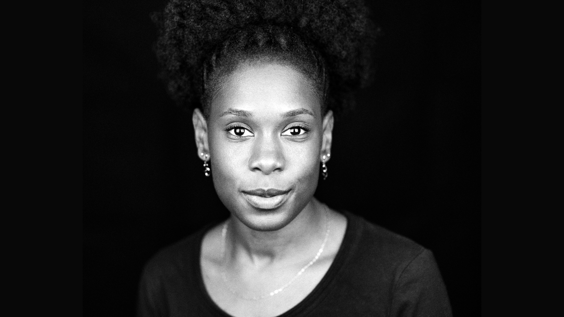 A black and white photo of a woman with tight curls looking to camera