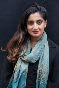 A woman with red lips and dark hair looks straight on