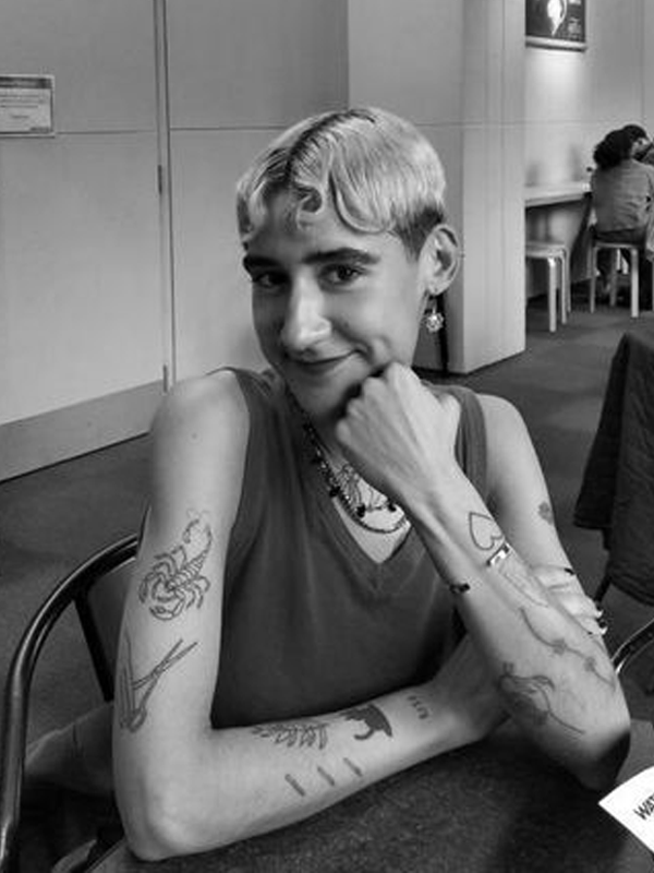 Valentina wears a sleeveless vest, arms showing a heart, scorpion, fern and other tattoos.